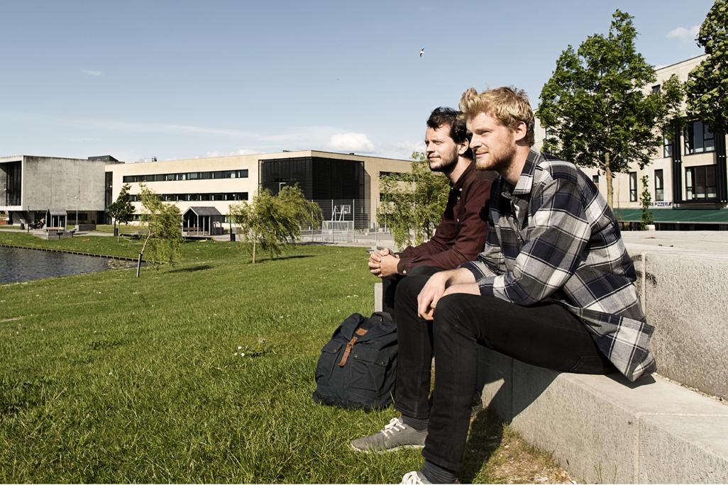 to mandlige studerende kigger ud over campus sø